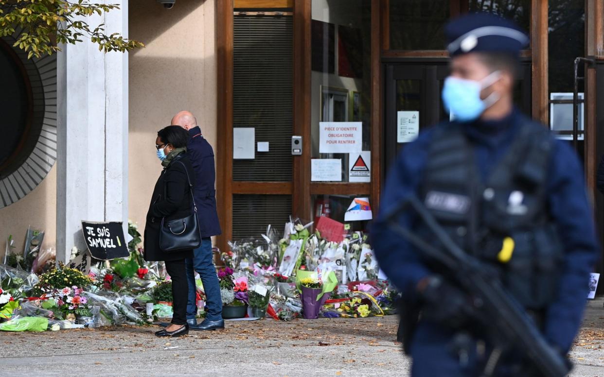 People look at flowers in France laid in homage to slain history teacher Samuel Paty - ANNE-CHRISTINE POUJOULAT /AFP