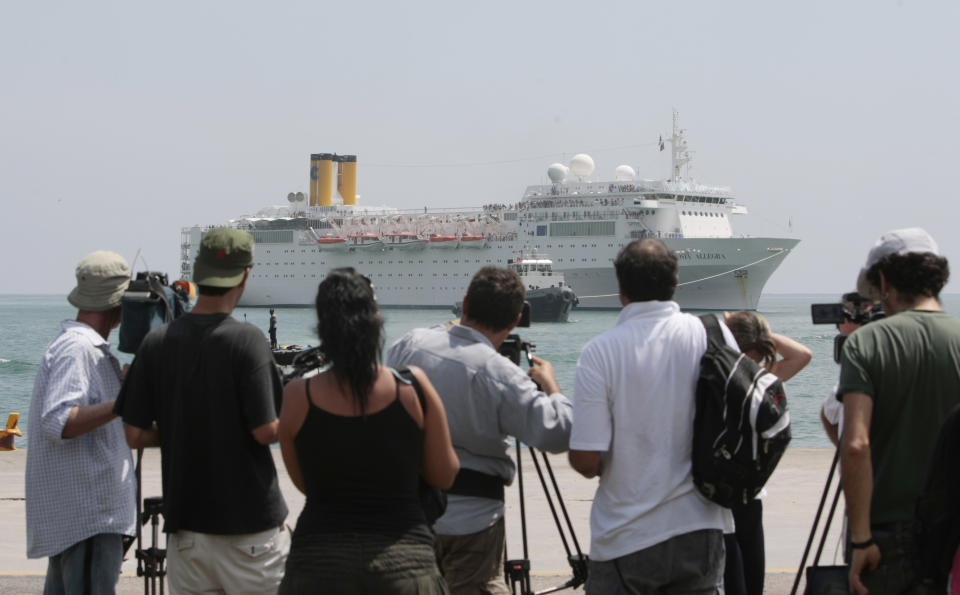 Members of the media and onlookers watch the Costa Allegra cruise ship as it is towed in Victoria harbor, Seychelles Island, Thursday, March 1, 2012. The disabled cruise ship arrived in port in the island nation of the Seychelles on Thursday morning after three days at sea without power. (AP Photo/Gregorio Borgia)