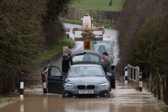 A local farmer helps rescue a stranded motorist from a flood on Hamilton Road in Leicester