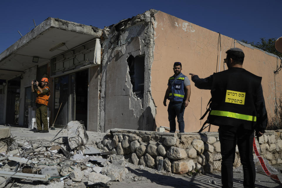 Israeli security forces and property tax officials examine a damaged store after it was hit by a rocket fired from the Gaza Strip, in Netivot, southern Israel, Tuesday, Jan. 16, 2024. (AP Photo/Leo Correa)