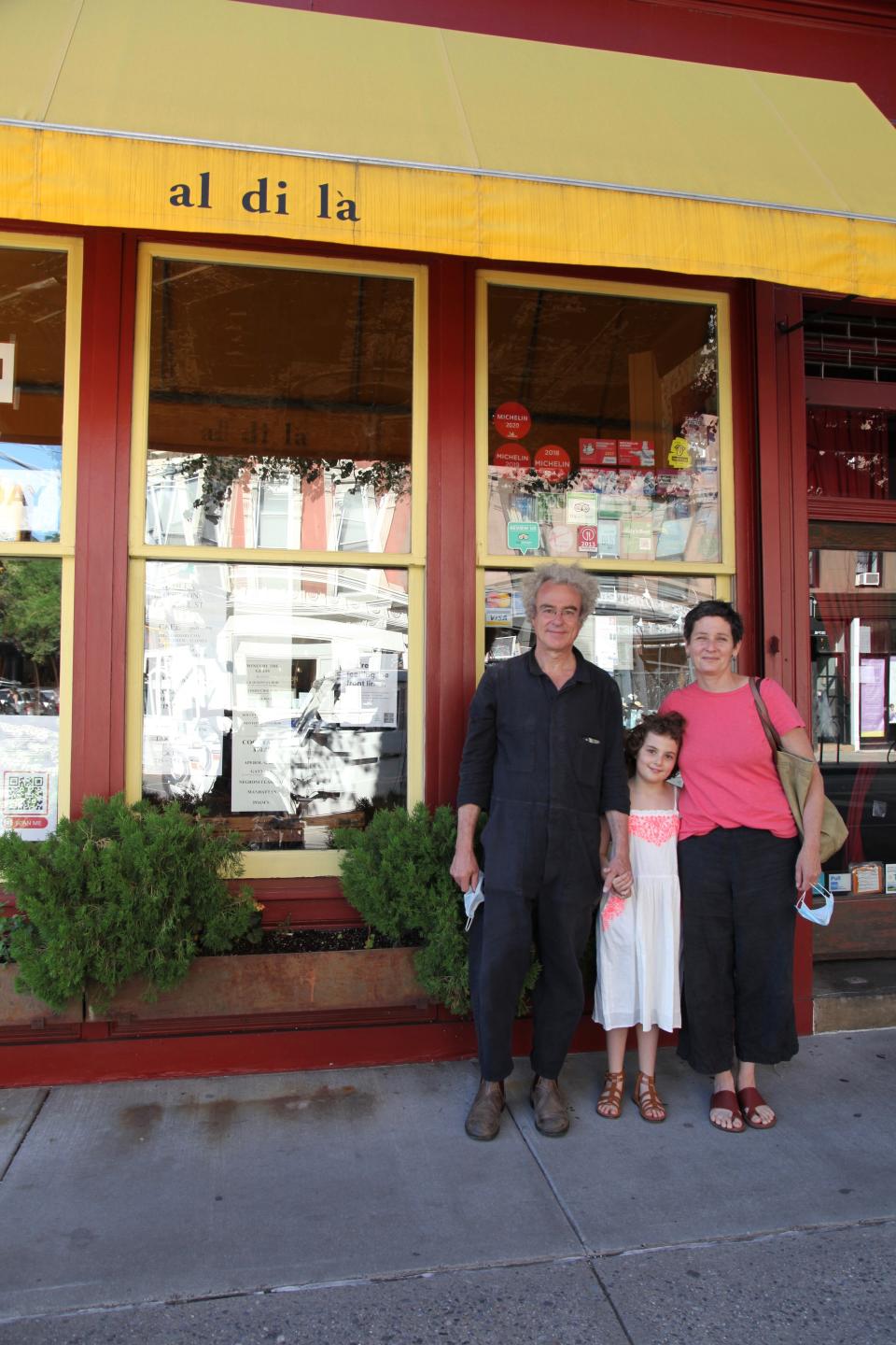 In this June 14, 2020 photo, Emiliano Coppa, left, and chef Anna Klinger pose with their daughter outside their trattoria, Al di La, in the Park Slope neighborhood in the Brooklyn borough of New York. The coronavirus has decimated the restaurant industry, leaving millions unemployed and shuttering spots for good. Many dine-in restaurants have turned to delivery or takeout, like Al di La. (Lisa Tolin via AP)