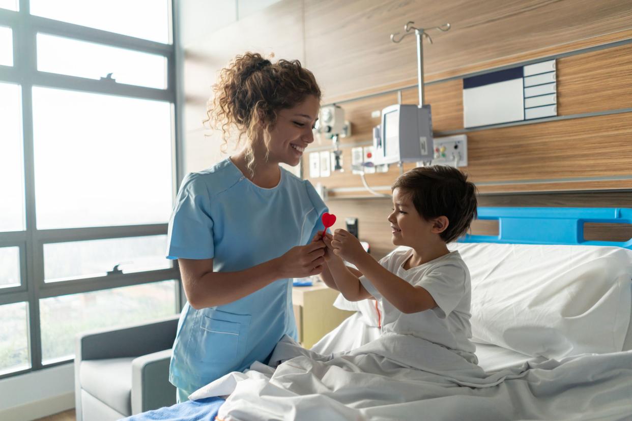 young beautiful nurse giving a lollipop to pediatrics hospitalized smiling child patient