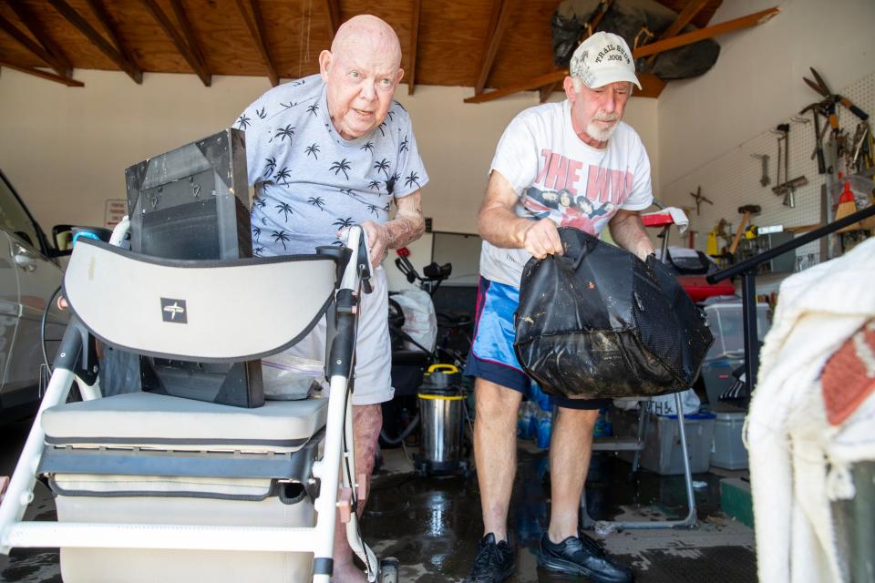 Budd Shcmittel, right, helps his 82-year-old neighbor, Bill Dobb, clean up water damage Monday in Dobb's garage in the Canyon Mobile Home Community in Cathedral City. Dozens of homes in the neighborhood had flooding during Tropical Storm Hilary.