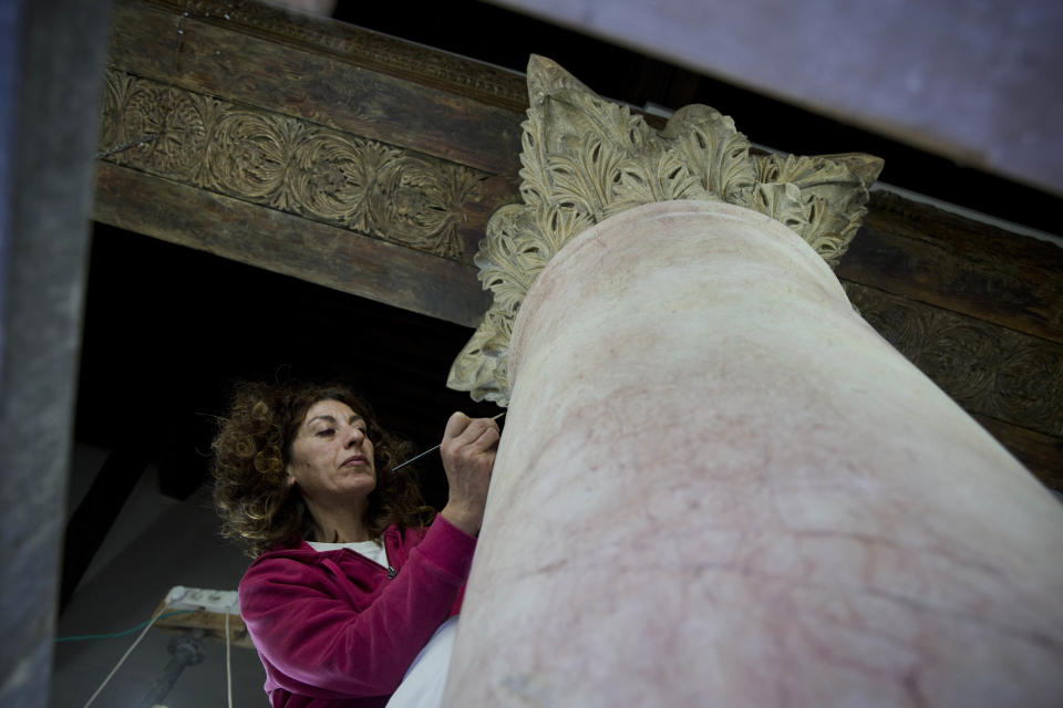 In this Thursday, Dec. 6, 2018 photo, a restoration expert works on a granite column inside the Church of the Nativity, built atop the site where Christians believe Jesus Christ was born, in the West Bank City of Bethlehem. The renovation is lifting spirits in the biblical town of Bethlehem ahead of Christmas, offering visitors a look at ancient mosaics and columns that have been restored to their original glory for the first time in 600 years. (AP Photo/Majdi Mohammed)