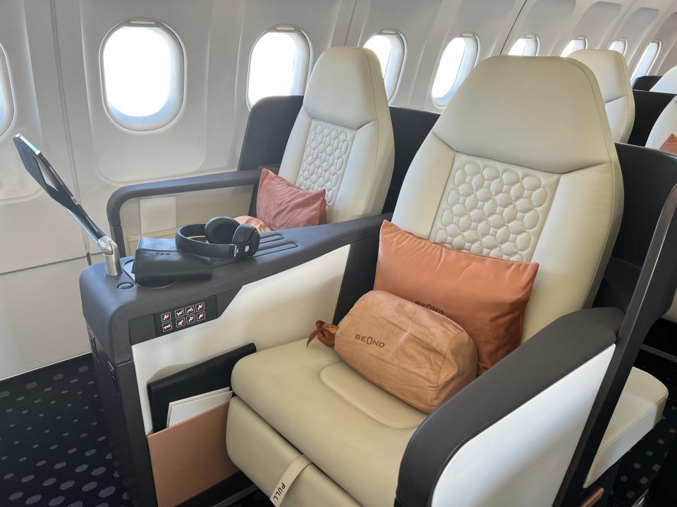 Two seats on a Beond A319 in cream leather with orange cushions embossed with the logo