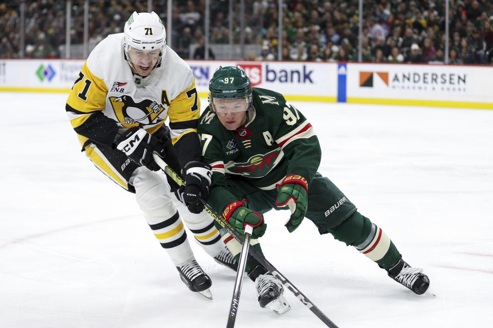 Pittsburgh Penguins center Evgeni Malkin, left, and Minnesota Wild left wing Kirill Kaprizov (97) compete for the puck during the first period of an NHL hockey game Friday, Feb. 9, 2024, in St. Paul, Minn. (AP Photo/Matt Krohn)