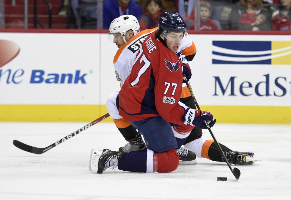 Washington Capitals right wing T.J. Oshie (77) reaches for the puck against Philadelphia Flyers defenseman Mark Streit, back, of Switzerland, during the first period of an NHL hockey game, Sunday, Jan. 15, 2017, in Washington. (AP Photo/Nick Wass)