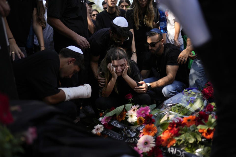 Mourners gather around the grave of May Naim, 24, during her funeral in Gan Haim, central Israel, Wednesday, Oct. 11, 2023. Naim and at least 260 more Israelis were killed by Hamas militants on Saturday at a rave near Kibbutz Re'im, close to the Gaza Strip's separation fence with Israel as the militant Hamas rulers of the territory carried out an unprecedented, multi-front attack that killed over 1,000 Israelis. (AP Photo/Francisco Seco)