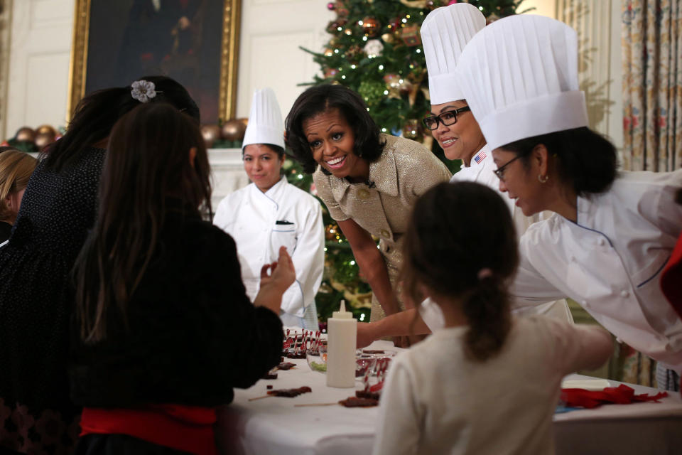 U.S. first lady Michelle Obama (C) participates in craft activities with military children at the State Dining Room after a preview of the 2012 White House holiday decorations November 28, 2012 at the White House in Washington, DC. The first lady welcomed military families, including Gold Star and Blue Star parents, spouses and children, to the White House for the first viewing of the 2012 holiday decorations. (Photo by Alex Wong/Getty Images)