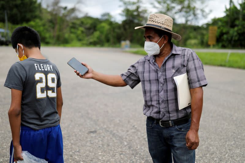 Juan holds his phone with a call from her wife Elida as their disabled 12-year-old son Gustavo walks away to avoid the conversation with her, during their reunion in Peten
