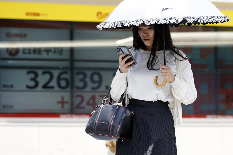 A person walks near an electronic stock board showing Japan's Nikkei 225 index at a securities firm Tuesday, July 18, 2023, in Tokyo. Shares were mostly lower Tuesday in Asia as optimism over a Wall Street rally was countered by worries about the Chinese economy. (AP Photo/Eugene Hoshiko)