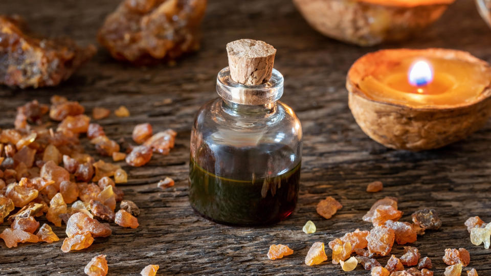 A bottle of myrrh essential oil next to a candle