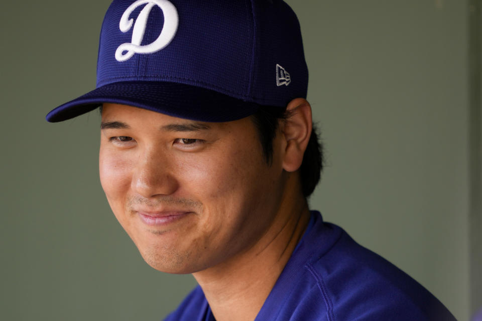 El bateador designado de los Dodgers de Los Ángeles Shohei Ohtani sonríe en el dugout antes de un entrenamiento de primavera contra los Rangers de Texas el miércoles 28 de febrero de 2024 en Surprise, Arizona. (AP Foto/Lindsey Wasson)