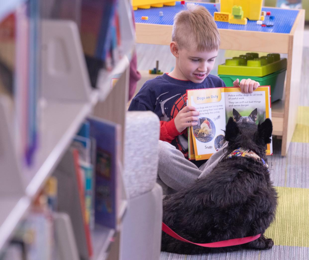 Marshall Wheeler, 7, shows the pictures in a book to Gibson, a Scottish terrier, during a Pups and Pages reading event at the Stark Library East Canton branch.