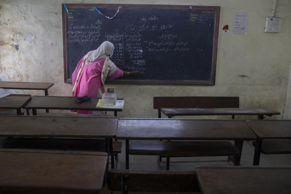 A teacher working at a government school gives an online class inside an empty class room in Dharavi, Asia's largest slum in Mumbai, India, Tuesday, Jan. 4, 2022. Amid a surge in COVID-19 cases in Mumbai, including the Omicron variant, the civic body on Monday decided to shut schools of all mediums for classes 1 to 9 and 11 till January 31, a civic official said. (AP Photo/Rafiq Maqbool)