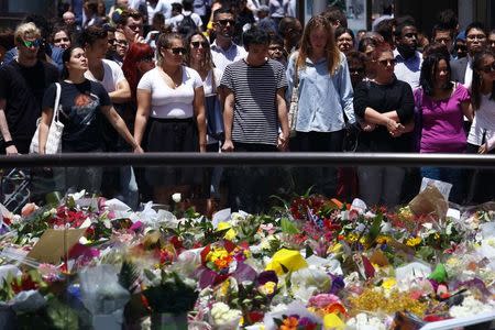 A group of people react after they placed floral tributes amongst thousands of others near the cafe in central Sydney December 16, 2014 where hostages were held for over 16-hours. REUTERS/David Gray