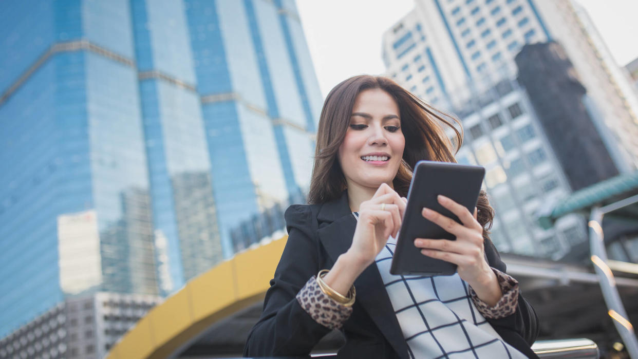 Portrait of successful smart business woman looking confident and smiling holding tablet computer.