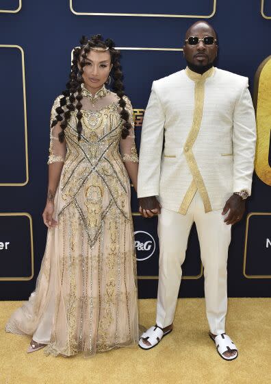 Jeannie Mai Jenkins in intricate gold gown holding hands with Jeezy in a white tunic and pants