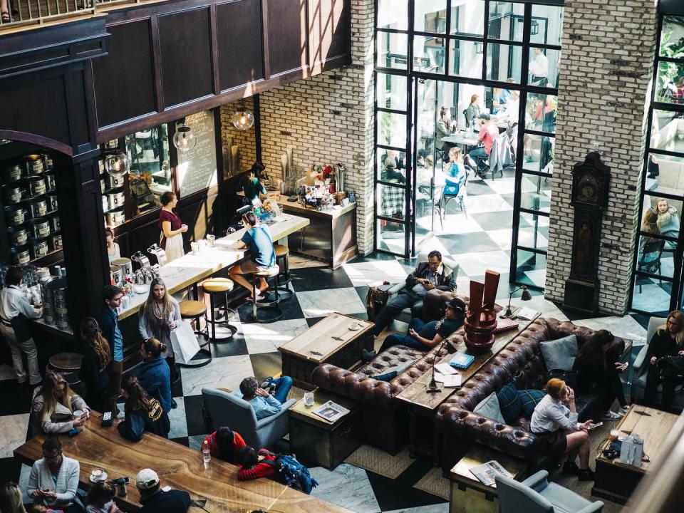 View from a balcony down into a busy café where most people are looking at their phones