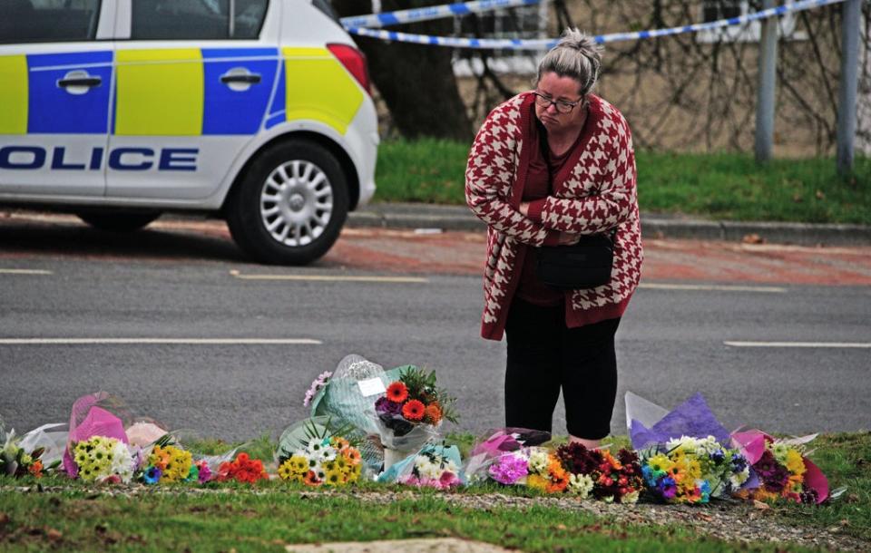 A woman lays flowers on Sheepstor Road in Plymouth after a woman’s body was found (Ben Birchall/PA) (PA Wire)