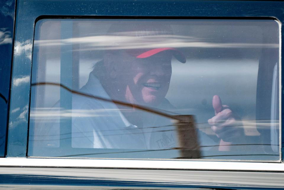 Former President Donald Trump gives a thumbs-up from his limousine as he departs Trump International Golf Club in West Palm Beach, Florida, on April 1, 2023.