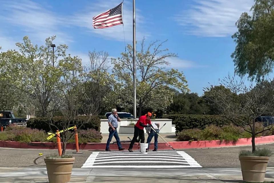 Workers use white paint to remove rainbow displays on speed bumps and crosswalks at Santa Ynez Valley Union High School.