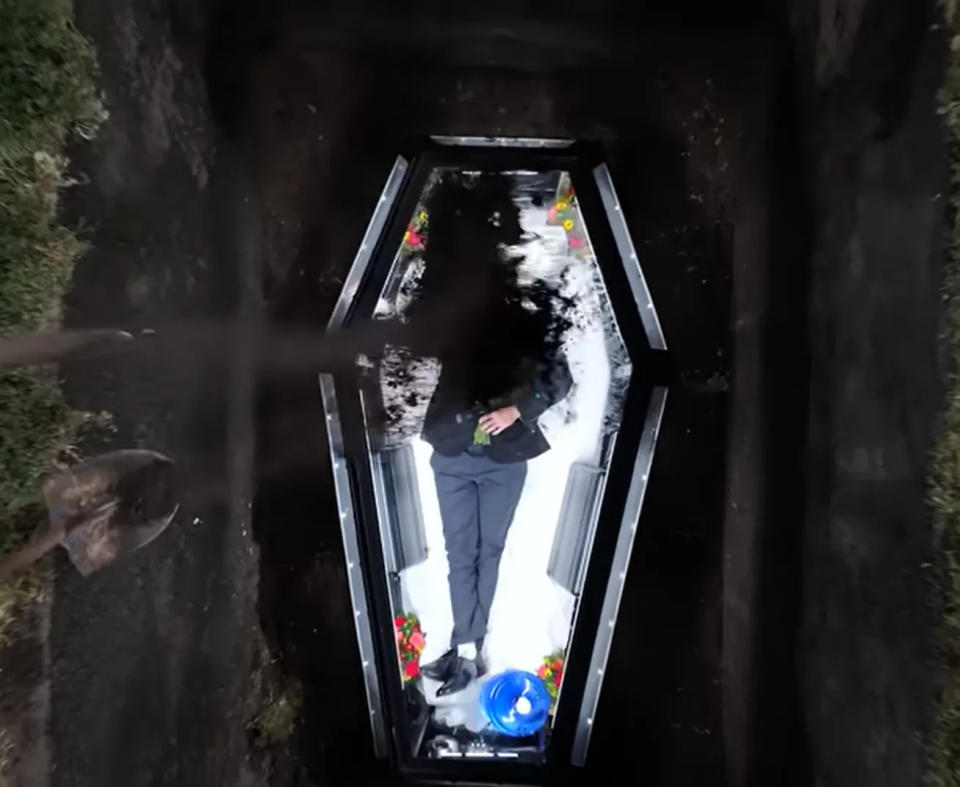 <strong>「MrBeast」煞有介事地穿上西裝，將自己和水、糧食關在地底下的透明棺材裡。（圖／翻攝自YouTube@MrBeast）</strong>