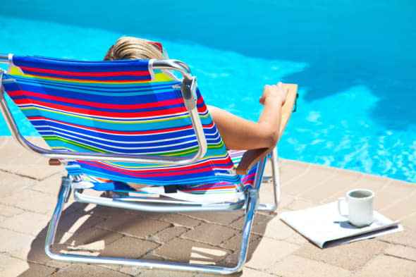 The woman is sitting near the pool