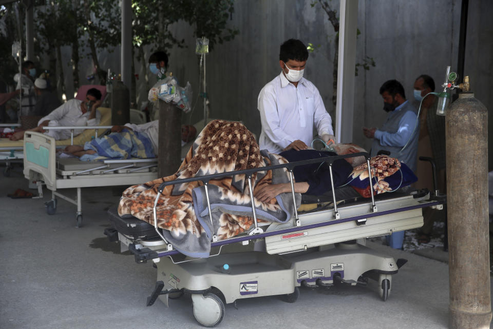 A man helps his father to drink juice at the Afghan-Japan Communicable Disease Hospital, for COVID-19 patients, in Kabul, Afghanistan, Thursday June 18, 2020. Afghan media reported last week that several COVID-19 patients died in government hospitals due to a shortages of medical oxygen, though the government denied the reports. (AP Photo/Rahmat Gul)