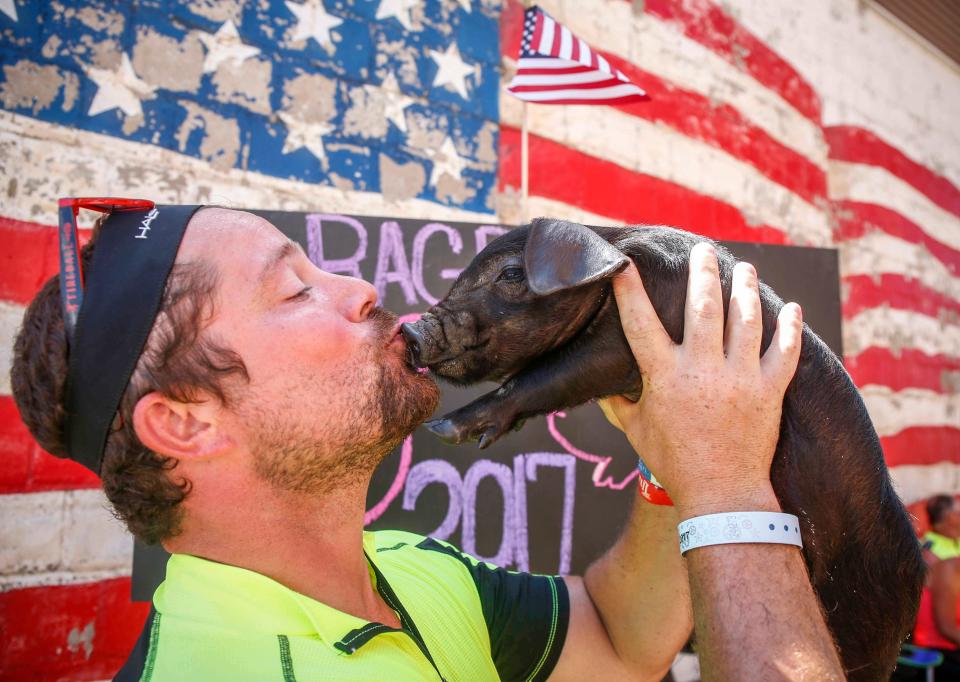 Zach Wigle of Solon kisses a baby pig Eggs at the Swine Cuddles booth in West Bend during RAGBRAI on  July 24, 2017.