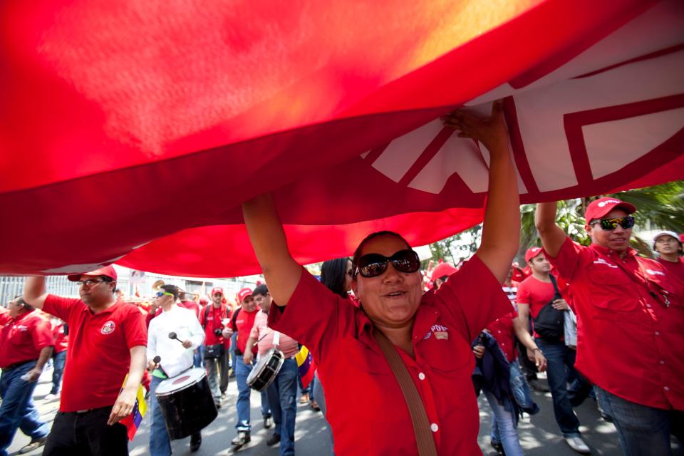 Employees of Petroleos de Venezuela, PDVSA, work together to hold up their red banner as they walk during a pro-government march in Caracas, Venezuela, Tuesday, Feb. 18, 2014. The Venezuelan government accuses the Obama administration of siding with student protesters it has blamed for violence that led to three deaths last week. Maduro claims the U.S. is trying to stir up unrest to regain dominance of South America's largest oil producer.(AP Photo/Alejandro Cegarra)