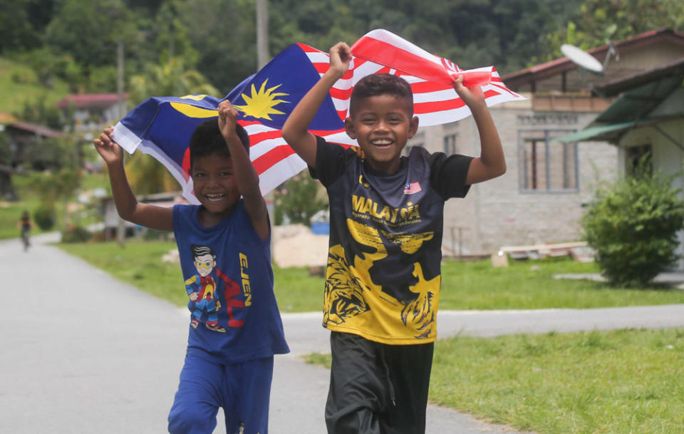 Children from Kampung Orang Asli Chadak, Ulu Kinta in Perak run with the Jalur Gemilang, September 15, 2021. — Picture by Farhan Najib