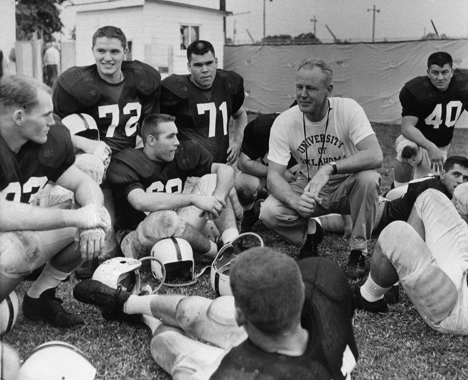 Oklahoma football coach Bud Wilkinson crouches among his players before starting practice for the New Year's Day game with Syracuse in the Orange Bowl at Miami, Fla., Dec. 27, 1958.  Some of the players are Marshall York (72), Ben Wells (71) and Wahoo McDaniel (40).  Others are unidentified. (AP Photo/Harold Valentine)