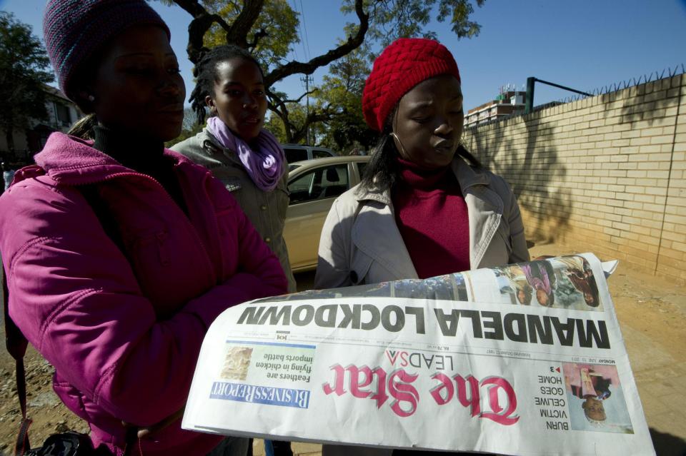 Varias mujeres leen un periódico que informa sobre el estado de salid de Mandela este 10 de junio en Pretoria, Sudáfrica