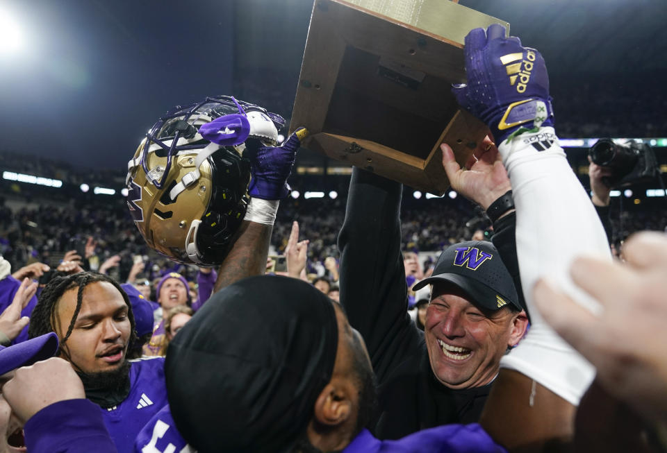 Washington head coach Kalen DeBoer, right facing, lifts the Apple Cup trophy after a win over Washington State in an NCAA college football game Saturday, Nov. 25, 2023, in Seattle. (AP Photo/Lindsey Wasson)