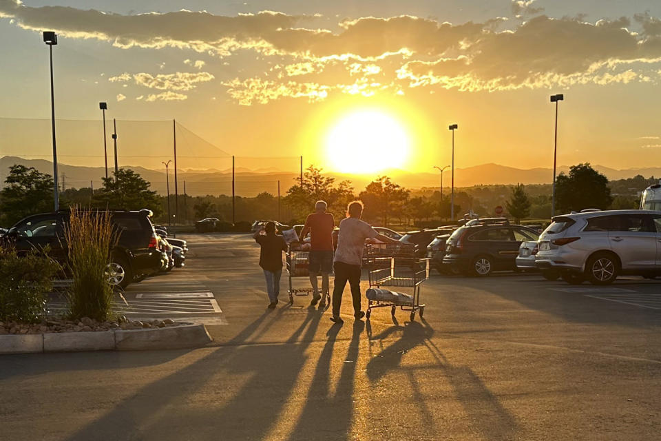 File - Shoppers cast long shadows as they head to their vehicles outside a Costco warehouse on July 11, 2023, in Sheridan, Colo. Although the Federal Reserve has sharply raised interest rates, consumer spending keeps growing at a healthy rate. (AP Photo/David Zalubowski, File)