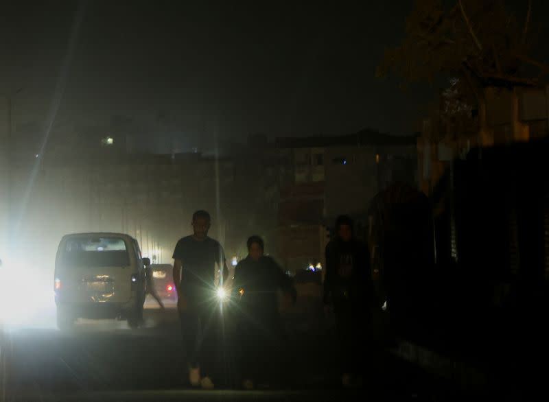 A general view shows vehicles and people walking through dark roads in the capital Cairo