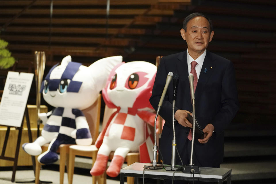 FILE - In this April 9, 2021, file photo, Japanese Prime Minister Yoshihide Suga, next to the mascots of Tokyo 2020 Olympic and Paralympic Games, speaks to the media after a government task force meeting for the new virus measures, at the prime minister's office in Tokyo. Japan said that it will raise the coronavirus alert level in Tokyo to allow tougher measures to curb the rapid spread of a more contagious variant ahead of the Summer Olympics. (AP Photo/Eugene Hoshiko, Pool, File)