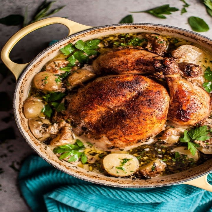 A pot roasted whole chicken with potatoes.