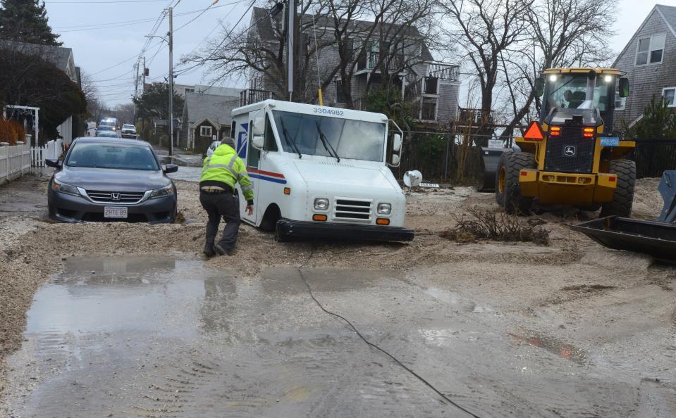 A flooded mail truck is hauled out of debris on Commercial Street in the east end of Provincetown, which was hard hit Friday by the morning high tide and high winds as a rain storm swept across the region.