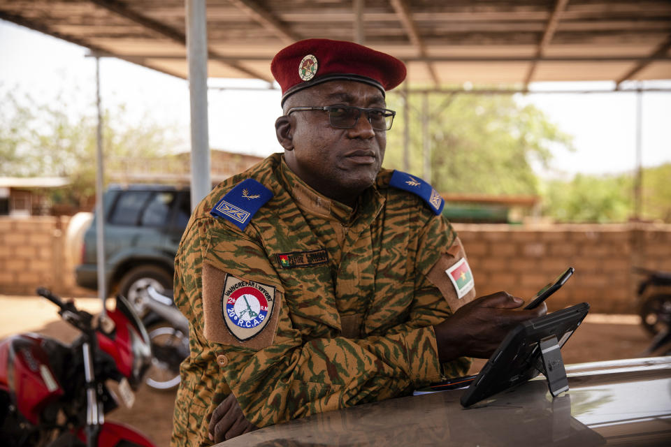 Salomon Tibiri, a pastor and military chaplain, checks his phone at the 10th RCAS barracks in Kaya, Burkina Faso, Saturday, April 10, 2021. Tibiri has been offering soldiers spiritual succor for more than 15 years. But he's never fielded as many calls from anxious soldiers as in recent years, when the army found itself under attack by Islamic extremist fighters. “Now (the soldiers) are busier, and when you approach them you feel their stress — much more stress,” he says. (AP Photo/Sophie Garcia)