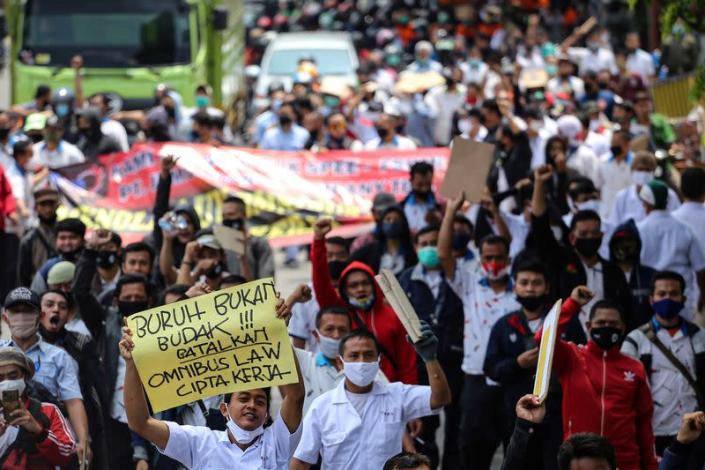 A man holds a sign reading "Labor is not a slave, cancel the omnibus bill of job creation" as members of Indonesian trade unions protest against the government's proposed labor reforms, in Tangerang