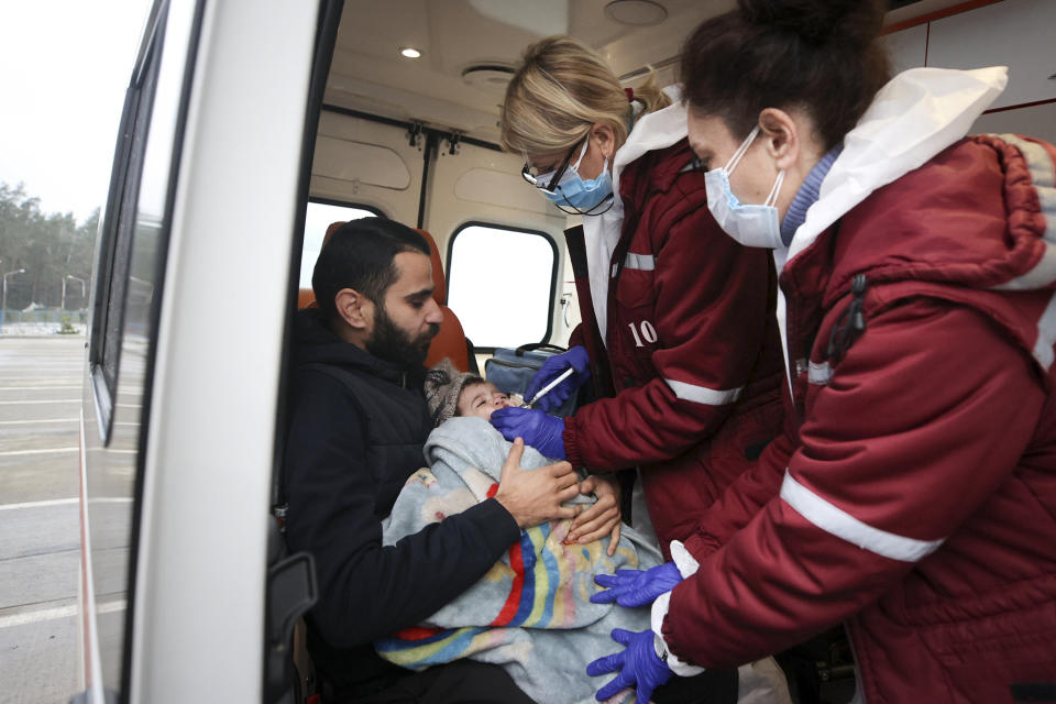 Belarusian medical staffers treat a baby inside an ambulance near a logistics center at the checkpoint "Kuznitsa" at the Belarus-Poland border near Grodno, Belarus, Sunday, Nov. 28, 2021. The West has accused Belarusian President Alexander Lukashenko of luring thousands of migrants to Belarus with the promise of help to get to Western Europe to use them as pawns to destabilize the 27-nation European Union in retaliation for its sanctions on his authoritarian government. Belarus denies engineering the crisis. (Leonid Shcheglov/BelTA via AP)