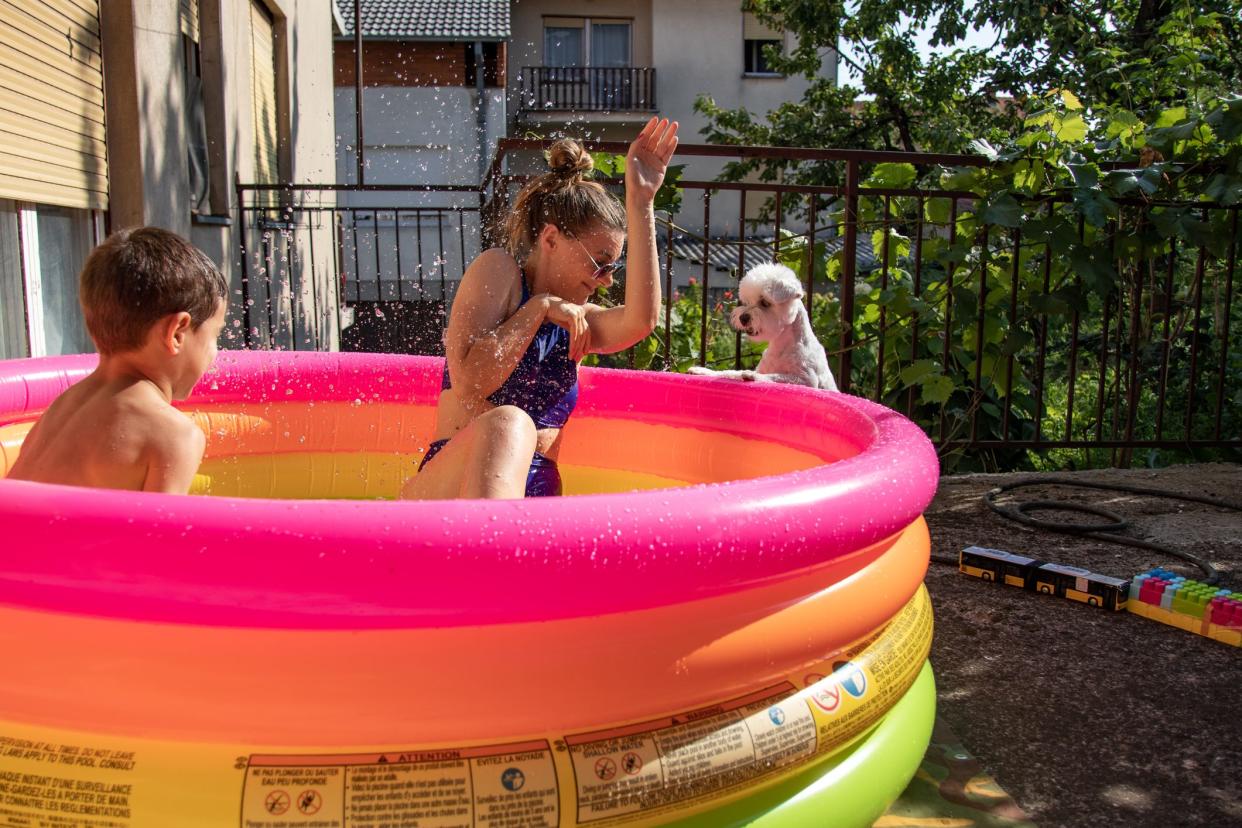 Family having fun in paddling pool during sunny summer day at backyard