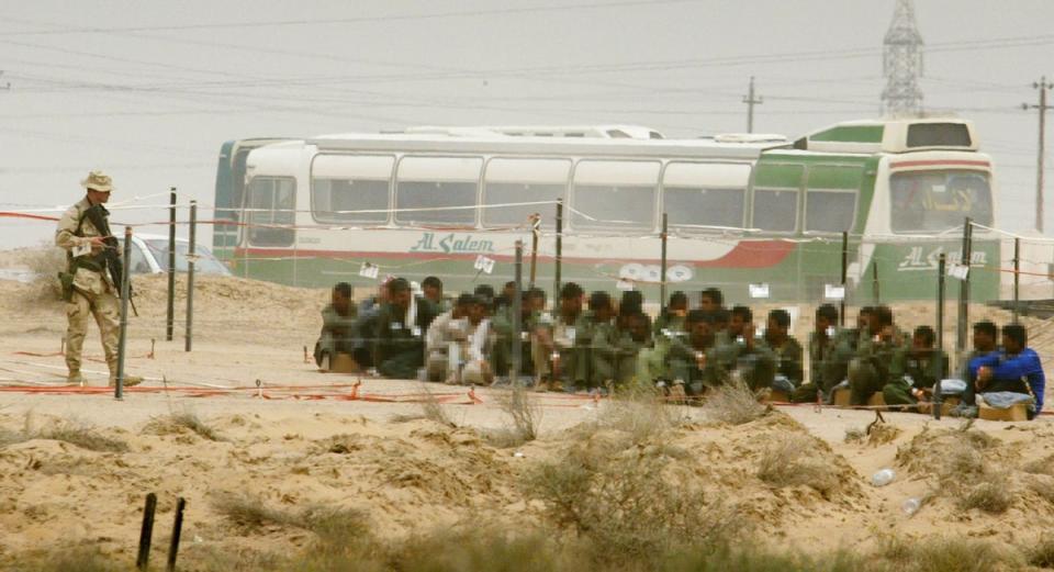 A soldier stands guard over prisoners of war at Camp Bucca on 8 April, 2003 (Getty)