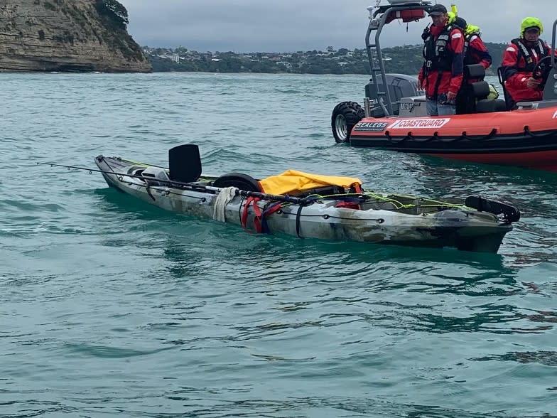 A fishing kayak is seen with the coast guard inspecting it in waters off Whangaparaoa. 