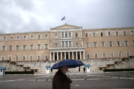 A man holding an umbrella makes his way in front of the Greek parliament during rainfall in Athens January 29, 2015. REUTERS/Alkis Konstantinidis