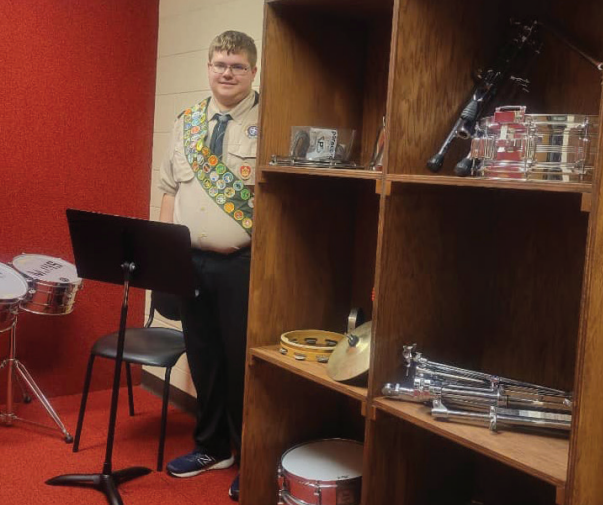 Dalton Clark, wearing his Boy Scout uniform, stands next to one of the finished cabinets.