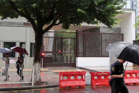 People shield themselves from the rain outside the U.S. Consulate in Guangzhou, China June 7, 2018. REUTERS/Sue-Lin Wong