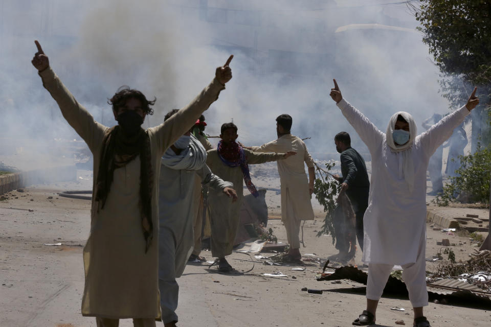 Supporters of Pakistan's former Prime Minister Imran Khan gestures as police fire tear gas to disperse them during a protest against the arrest of their leader, in Peshawar, Pakistan, Wednesday, May 10, 2023. A court has ruled that former Pakistani Prime Minister Imran Khan can be held for questioning for eight days. The decision Wednesday comes a day after the country’s popular opposition leader was dragged from a courtroom and arrested. His detention set off clashes between his supporters and police Tuesday. (AP Photo/Muhammad Sajjad)